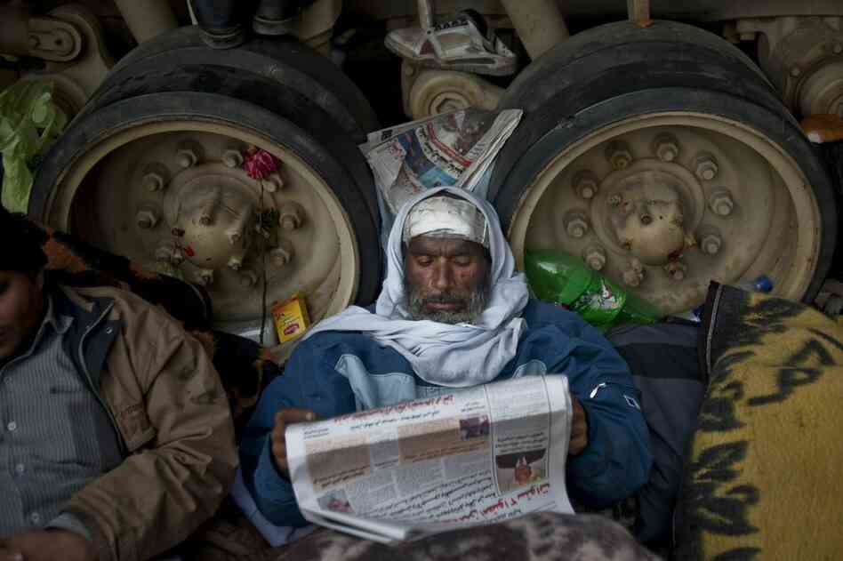 A protester reads a newspaper while resting against an army tank in Tahrir Square on Friday. 