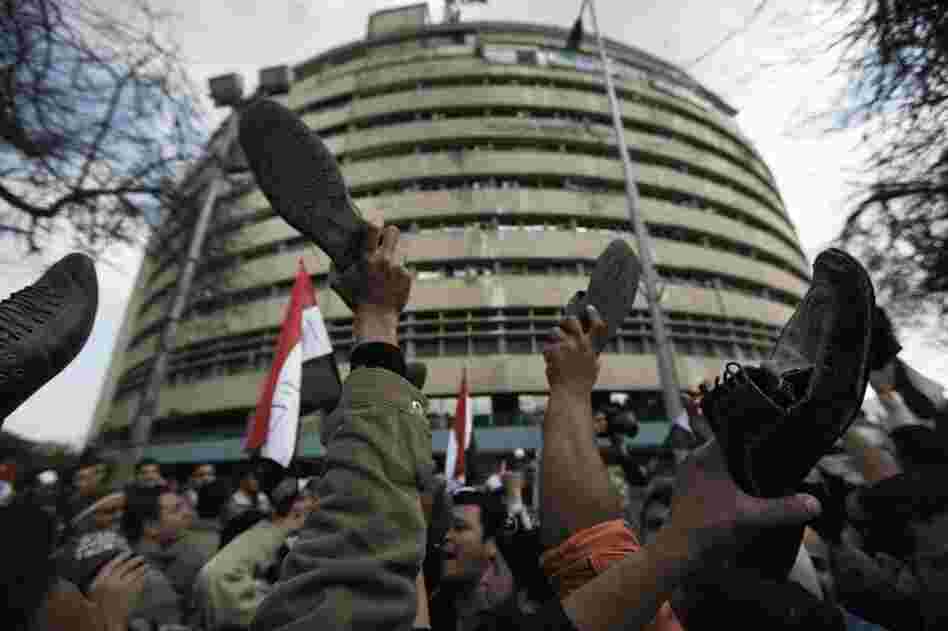 In a gesture of disrespect Friday, anti-government protesters raise their shoes in front of the Egyptian national TV building, which is currently secured by the Egyptian army. 