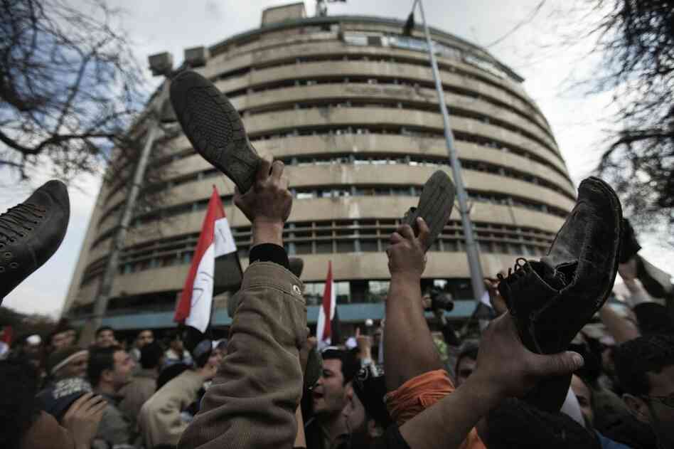 In a gesture of disrespect Friday, anti-government protesters raise their shoes in front of the Egyptian national TV building, which is currently secured by the Egyptian army. 
