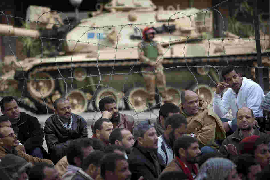 A soldier stands guard next to a tank as crowds protest in front of the state television building in downtown Cairo on Friday. 