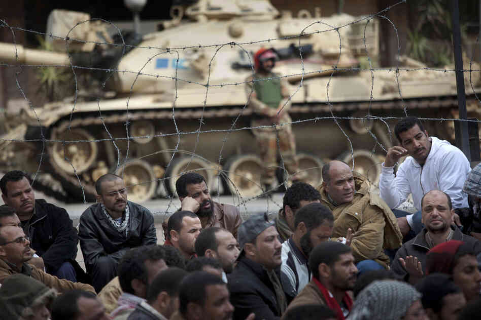 A soldier stands guard next to a tank as crowds protest in front of the state television building in downtown Cairo on Friday. 