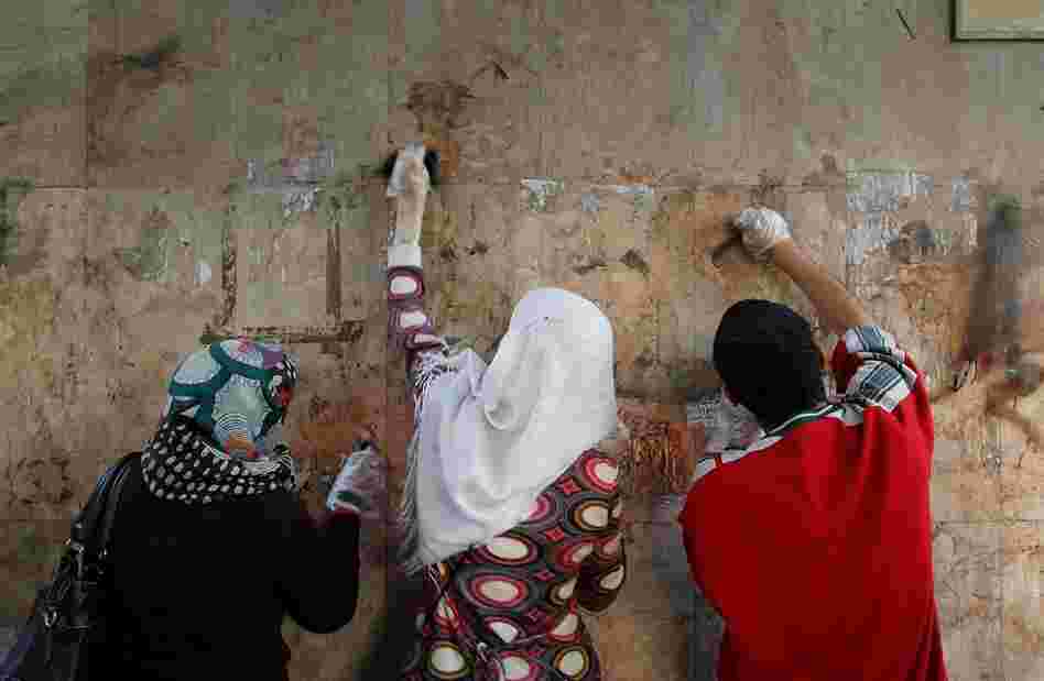 Volunteers scrub paint and graffiti off of a wall in Tahrir Square. Cleaning crews, both paid and unpaid, made quick work of cleanup where thousands of protesters lived and fought for more than two weeks. 