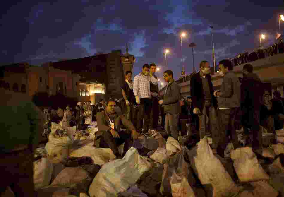 Egyptians stand on top of sacks of garbage collected from the streets of Tahrir Square in Cairo on Saturday. 