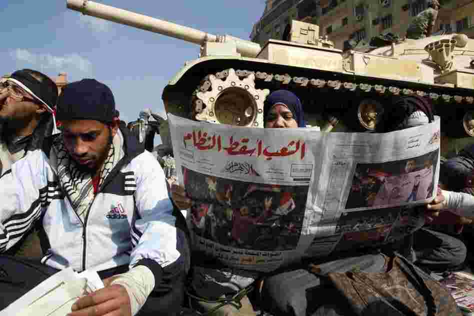Egyptians read about Friday's events in front a tank. 
