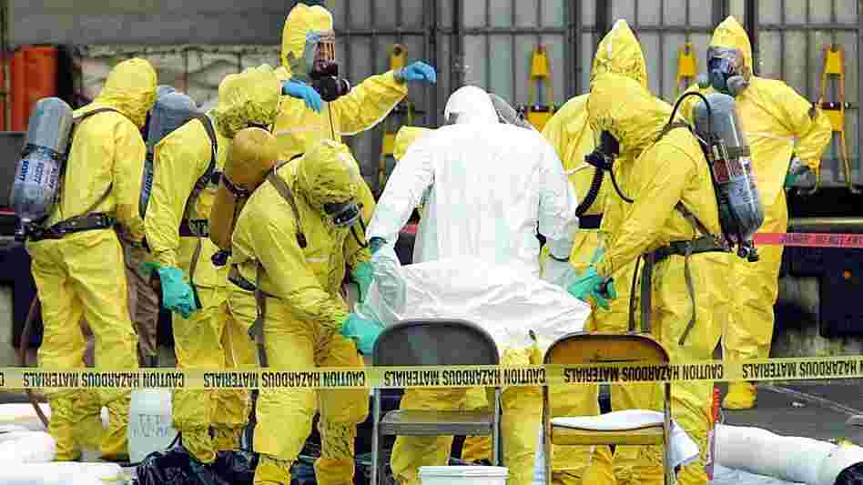 Members of a hazardous materials response team help to remove a hazardous materials suit from an investigator who had emerged from the U.S. Post Office in West Trenton, N.J., on Oct. 25, 2001. The post office was closed after two letters containing anthrax were traced back to this facility. Members of a hazardous materials response team help to remove a hazardous materials suit from an investigator who had emerged from the U.S. Post Office in West Trenton, N.J., on Oct. 25, 2001. The post office was closed after two letters containing anthrax were traced back to this facility.