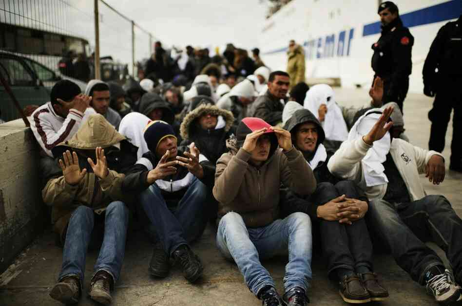 Tunisian immigrants who arrived on the island of Lampedusa wait to board a ship that will bring them to a reception center.