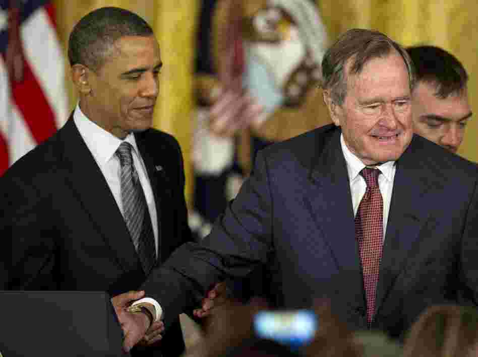 President Obama assists former President George H.W. Bush during todays Medal of Freedom ceremony at the White House.