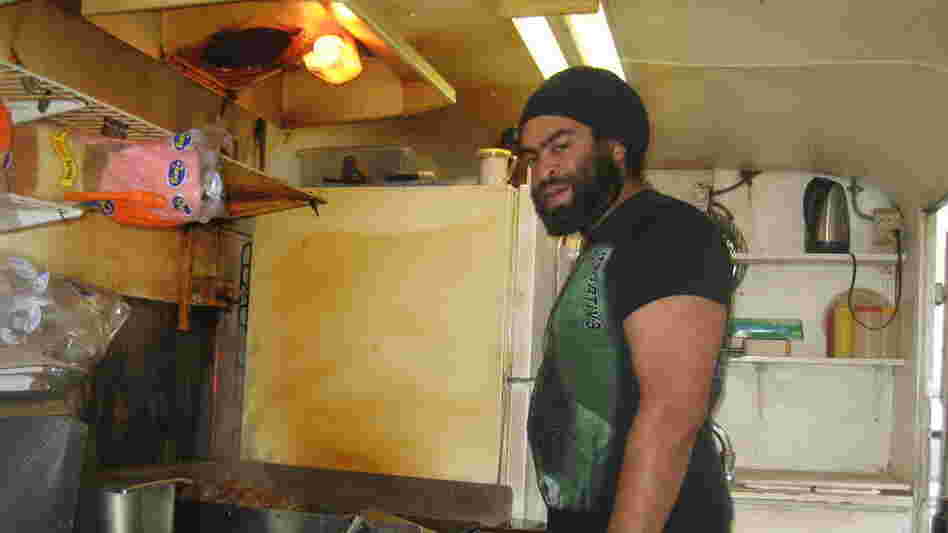 Quentin Gardiner huddles over the grill in a food cart in downtown, Portland. Gardiner is from Binghamton, N.Y., and says he moved to the city for the heavy metal rock scene.