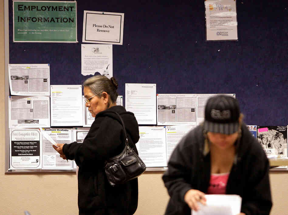 Job seekers read their resumes as they stand near a bulletin board with job posting fliers on it at the Arizona Workforce Connection West Valley Career Center in Phoenix. Foreign-born workers have had better employment prospects than U.S. natives.