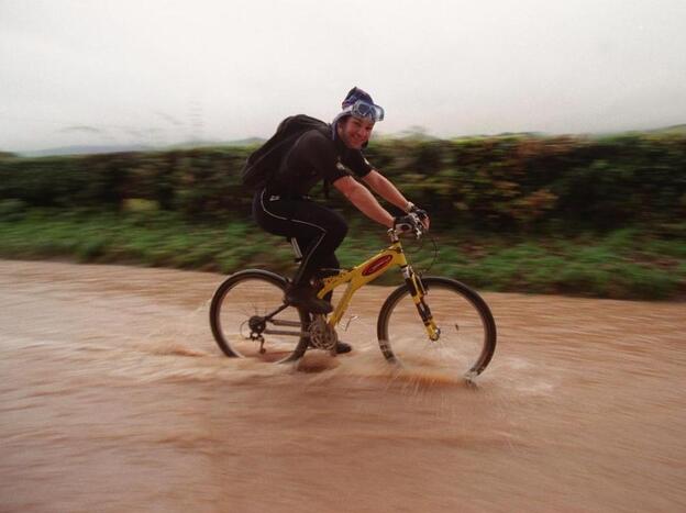 A cyclist wearing a wet suit cycles to work on Nov. 7, 2000, as roads in North Wales were impassable by vehicles. Computer models of the climate show that heavy rains were less likely to occur in a simulated world without global warming.