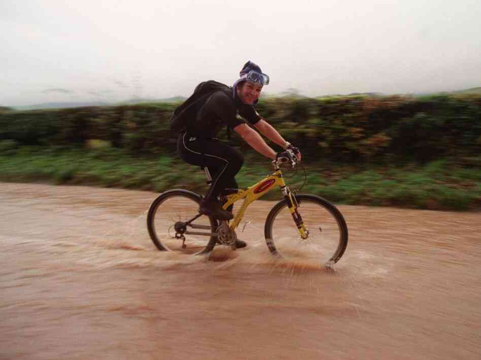 A cyclist wearing a wet suit cycles to work on Nov. 7, 2000, as roads in North Wales were impassable by vehicles. Computer models of the climate show that heavy rains were less likely to occur in a simulated world without global warming.