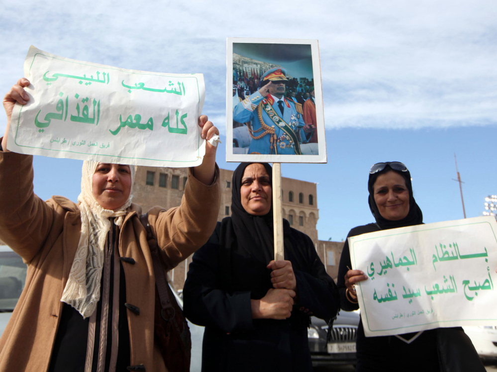 Libyan pro-government supporters hold a portrait of leader Moammar Gadhafi during a rally Wednesday in Tripoli.