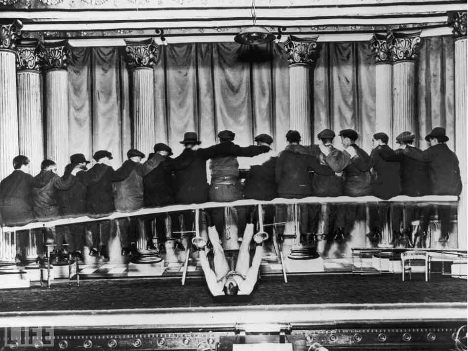 A strong man on his back lifts a group of men on a bench, circa, 1935. A strong man on his back lifts a group of men on a bench, circa, 1935.