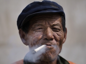 An elderly Chinese construction worker smokes a cigarette while taking a break from work in Beijing.