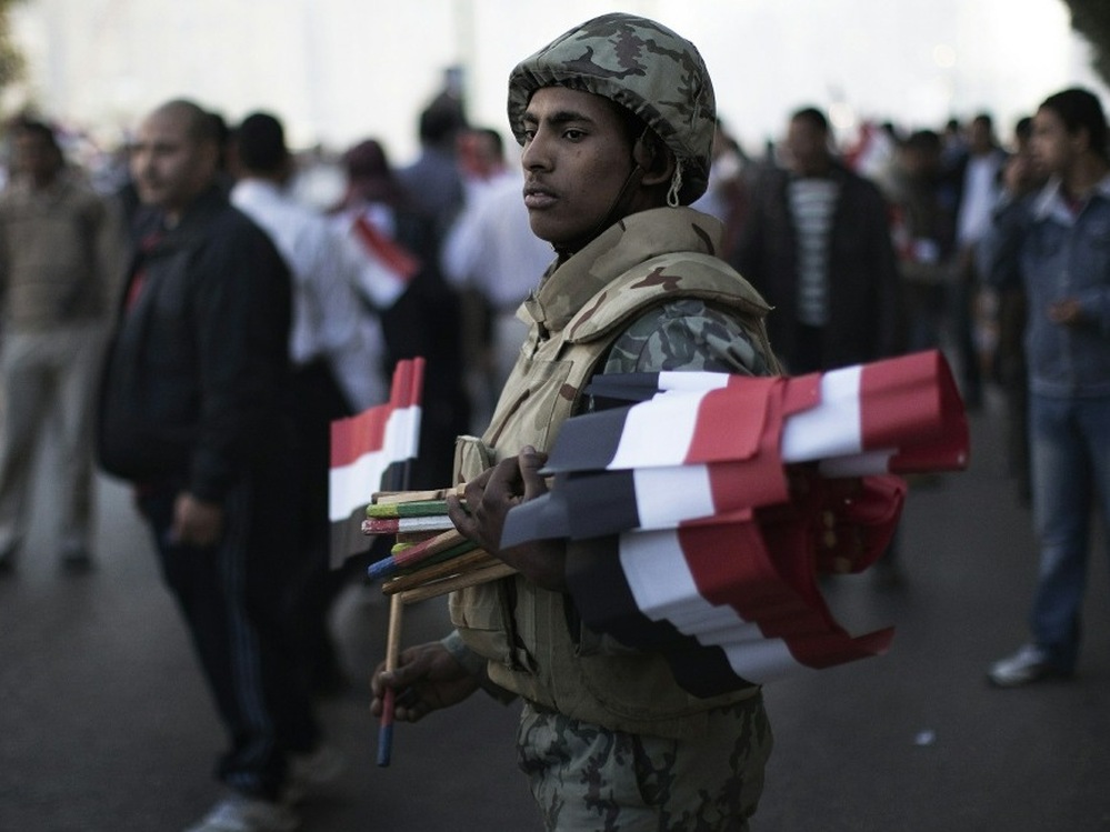 An Egyptian soldier greeted demonstrators with national flags today in Cairo's Tahrir Square.