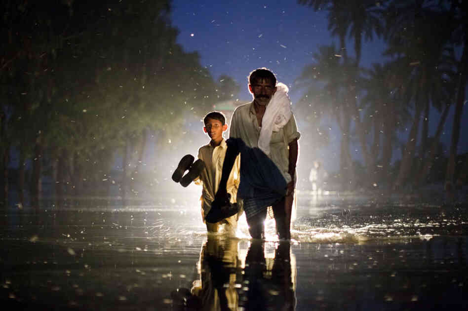 A Pakistani man and boy,  displaced by floods, walk through flood waters on Aug. 22, 2010 in the village of Baseera near Muzaffargarh in Punjab, Pakistan.