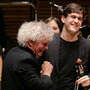 The Ensemble ACJW, conducted by Sir Simon Rattle (center), features musicians from the Academy, sponsored by Carnegie Hall and the Juilliard School. The violist to the right of Rattle is Nathan Schram. The Ensemble ACJW, conducted by Sir Simon Rattle (center), features musicians from the Academy, sponsored by Carnegie Hall and the Juilliard School. The violist to the right of Rattle is Nathan Schram.