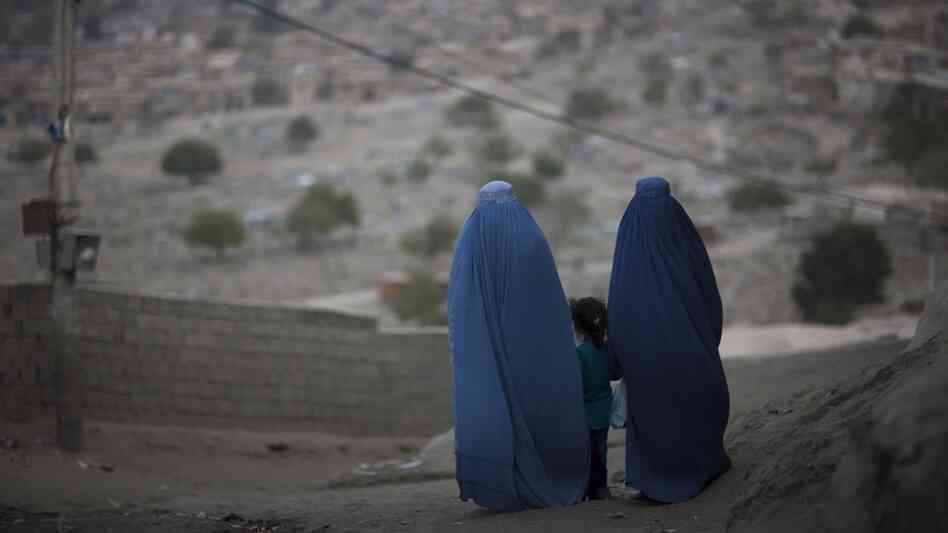 A girl stands among Afghan women clad in burqas  in Kabul last October.