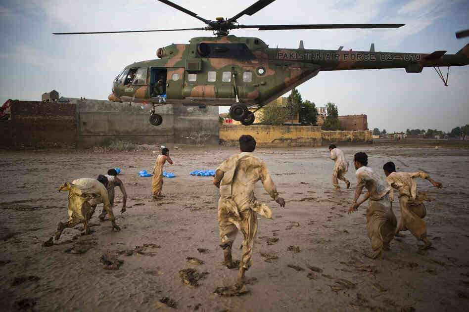 Flood victims scramble to recover water bottles dropped from a Pakistan Air force helicopter on August 2, 2010 in Nowshera, Pakistan.
