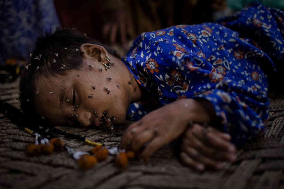 A young Pakistani girl, displaced by floods, and stranded on land only accessible by air, sleeps covered in flies, on a makeshift bed on August 27, 2010 in Garhi Khairo near Jacobabad in Sindh province, Pakistan.