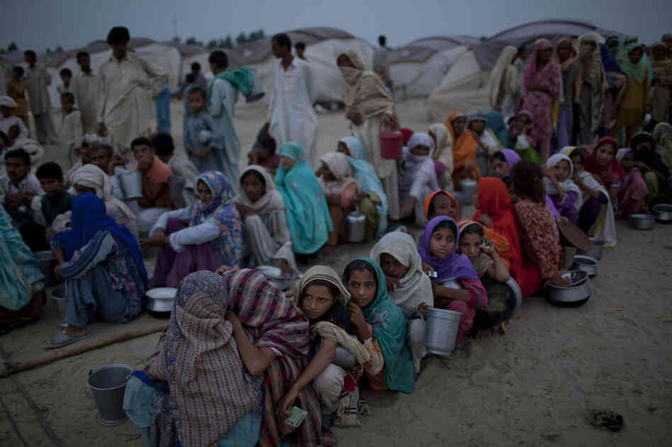 Villagers, displaced from their homes by flooding, hold empty containers as they queue for soup and relief rations on August 25, 2010 in the Sultan Colony Army flood relief camp near Muzaffargarh in Punjab, Pakistan.