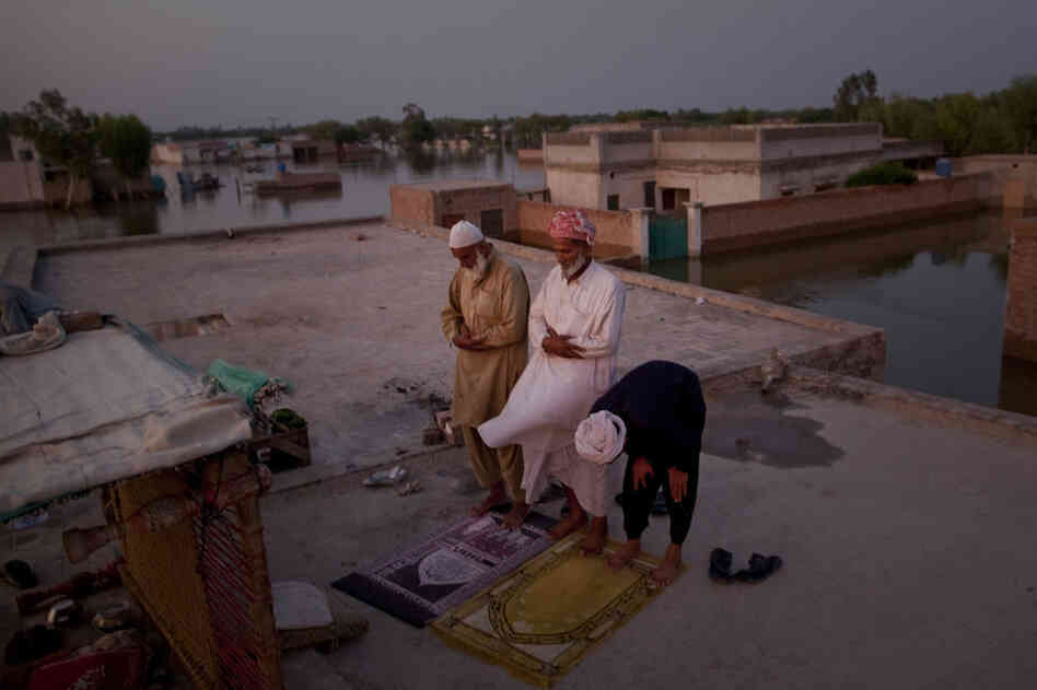 Pakistani villagers perform the Maghrib prayer, as they seek refuge on top of the roof of a Madrasa surrounded by flood waters, after Iftar or breaking fast in the month of Ramadan, on August 21, 2010 in the village of Vasandawali south of Muzaffargarh in Punjab, Pakistan.