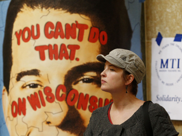 A protester looks on near a poster of Republican Gov. Scott Walker inside the state Capitol on Monday in Madison, Wis. Opponents to Gov. Walker's bill to eliminate collective bargaining rights for many state workers are taking part in their seventh day of protesting.