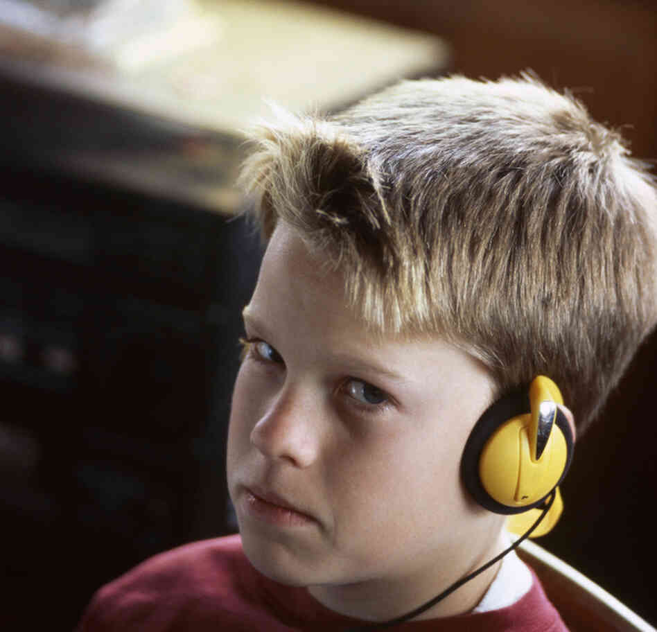 Boy sitting in chair, listening to music on headset Boy sitting in chair, listening to music on headset