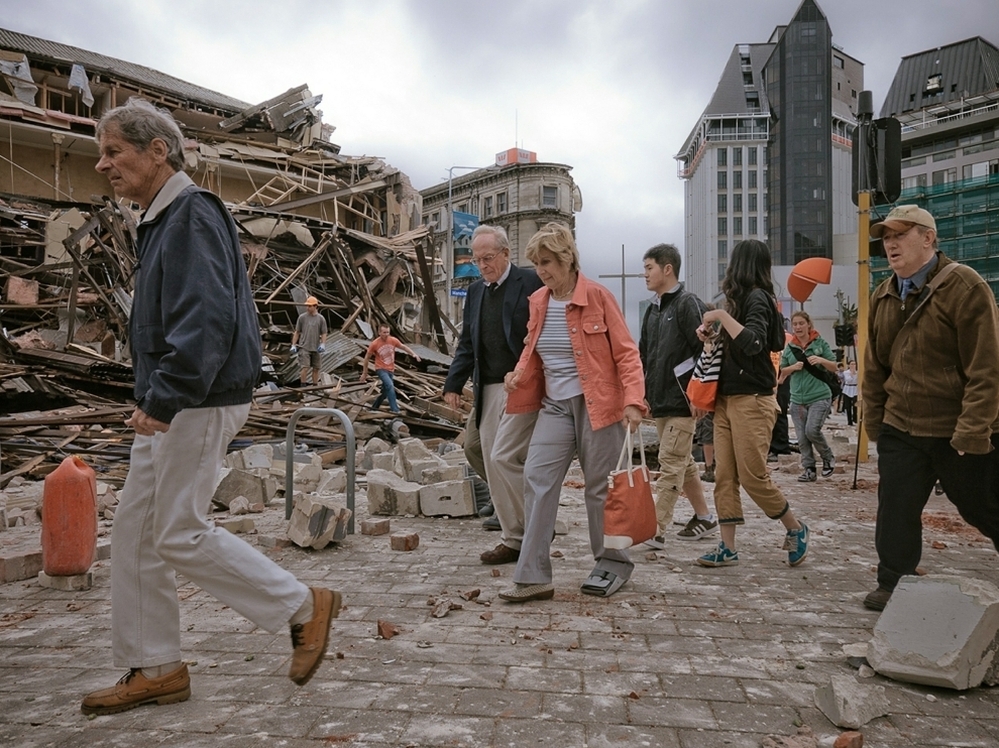 People walk through debris in the aftermath of a strong earthquake in Christchurch, New Zealand, Tuesday. The region is still recovering from a 7.1 quake in September.