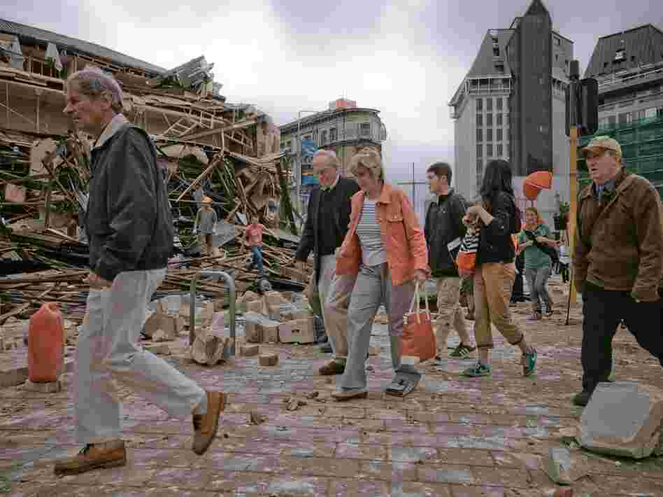 People walk through debris in the aftermath of a strong earthquake in Christchurch, New Zealand, Tuesday. The region is still recovering from a 7.1 quake in September.