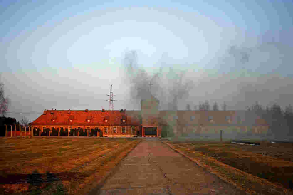 Coal smoke billows from the former main entrance to extermination camp Auschwitz II-Birkenau, which is now an active Catholic Church for the village of Brzezinkau ("Birkenau" in German).