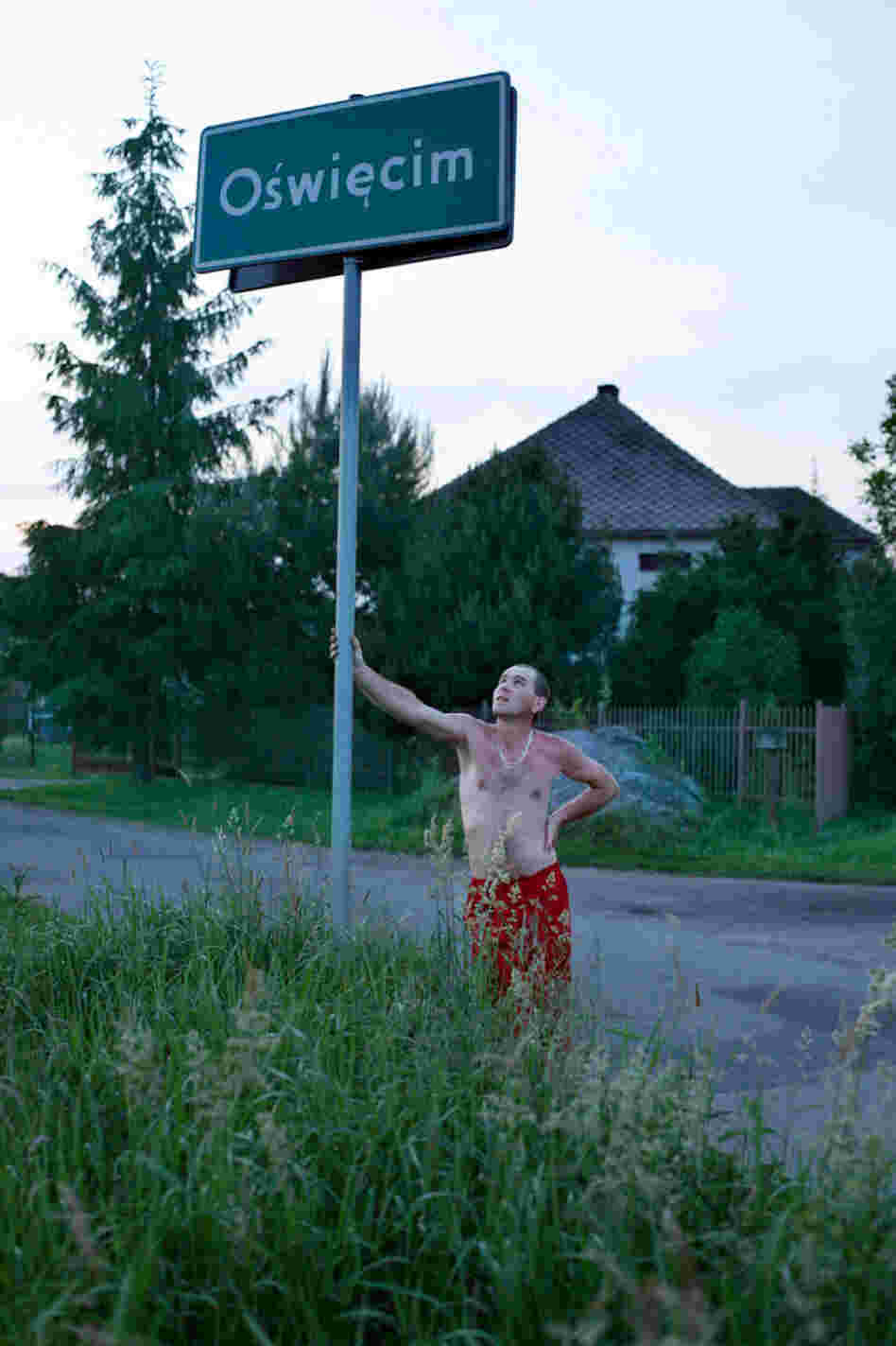 A man from a village bordering Oswiecim leans on a city limits sign for a portrait. A man from a village bordering Oswiecim leans on a city limits sign for a portrait.