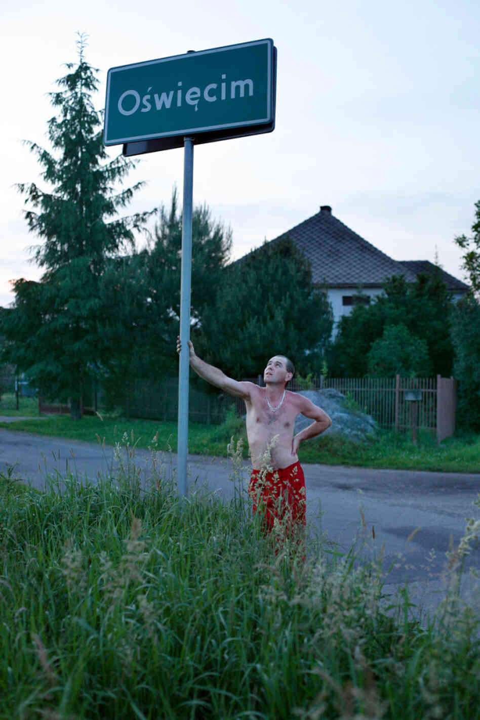 A man from a village bordering Oswiecim leans on a city limits sign for a portrait. A man from a village bordering Oswiecim leans on a city limits sign for a portrait.