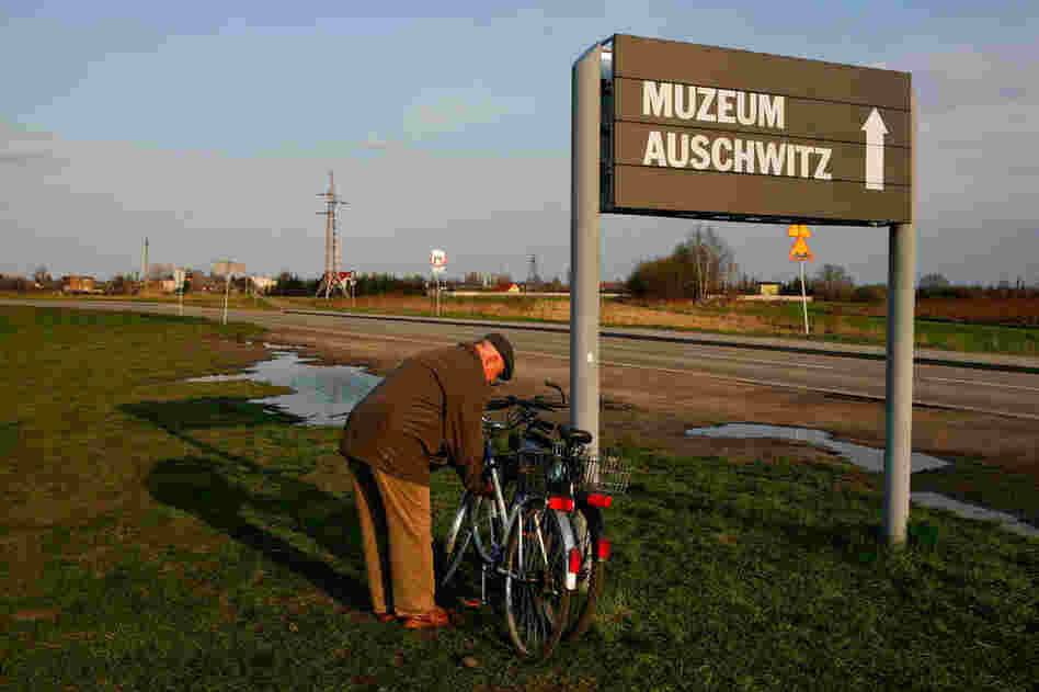 An elderly man from Oswiecim locks his bike to a sign at Auschwitz II-Birkenau that directs visitors to the Auschwitz museum site.