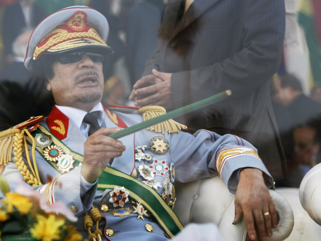 Sept. 1, 2009: Libyan leader Moammar Gadhafi gestures with a green cane as he takes his seat behind bulletproof glass for a military parade in Tripoli's Green Square.