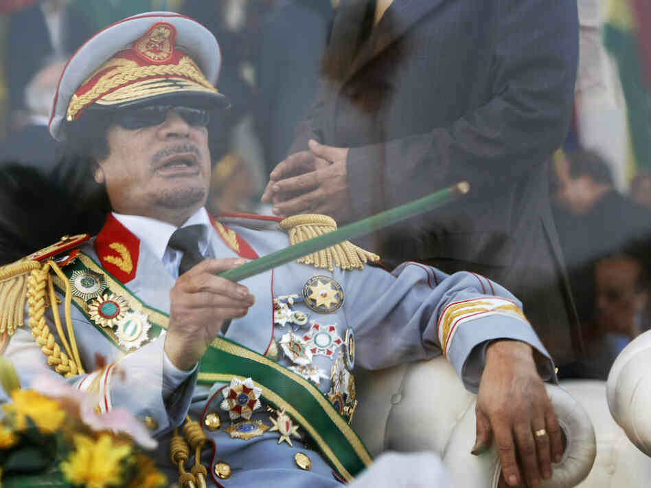 Sept. 1, 2009: Libyan leader Moammar Gadhafi gestures with a green cane as he takes his seat behind bulletproof glass for a military parade in Tripoli's Green Square.