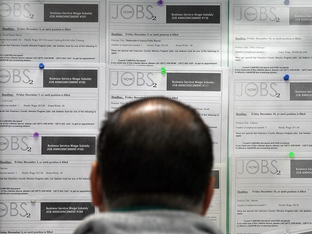 A job seeker looks at listings on a bulletin board.