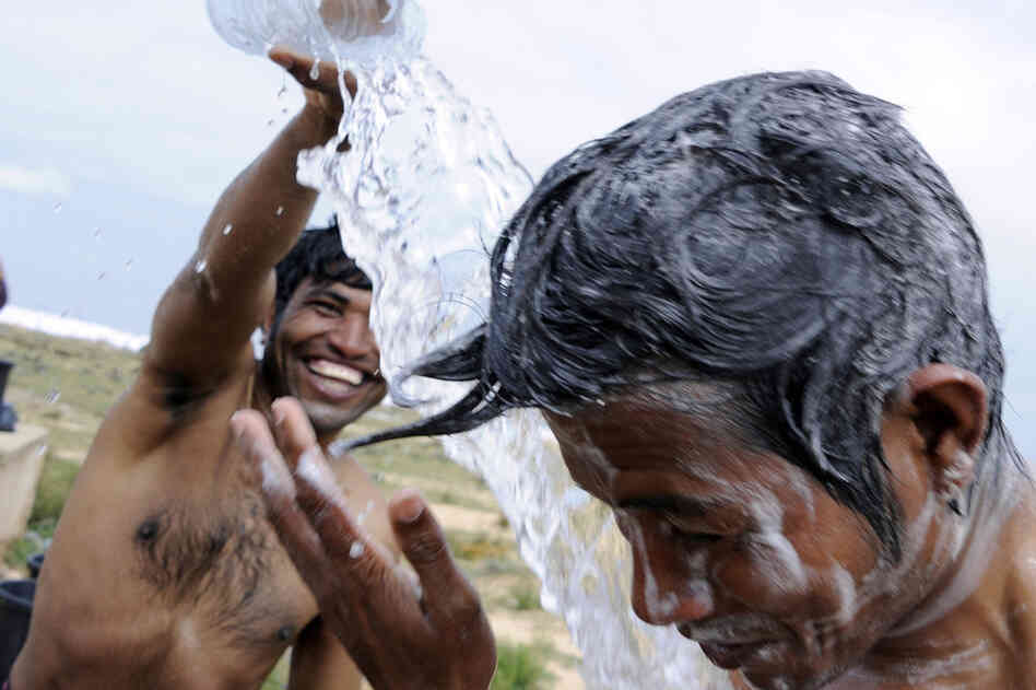 Refugees who fled Libya bathe in the Choucha refugee camp, near the Tunisian border town of Ras Jdir on Tuesday. The Red Cross and the United Arab Emirates plan to build two new camps on Tunisia's border. An estimated 100,000 mainly foreign migrants have crossed from Libya into Tunisia since Feb. 20, Tunisian officials said. 