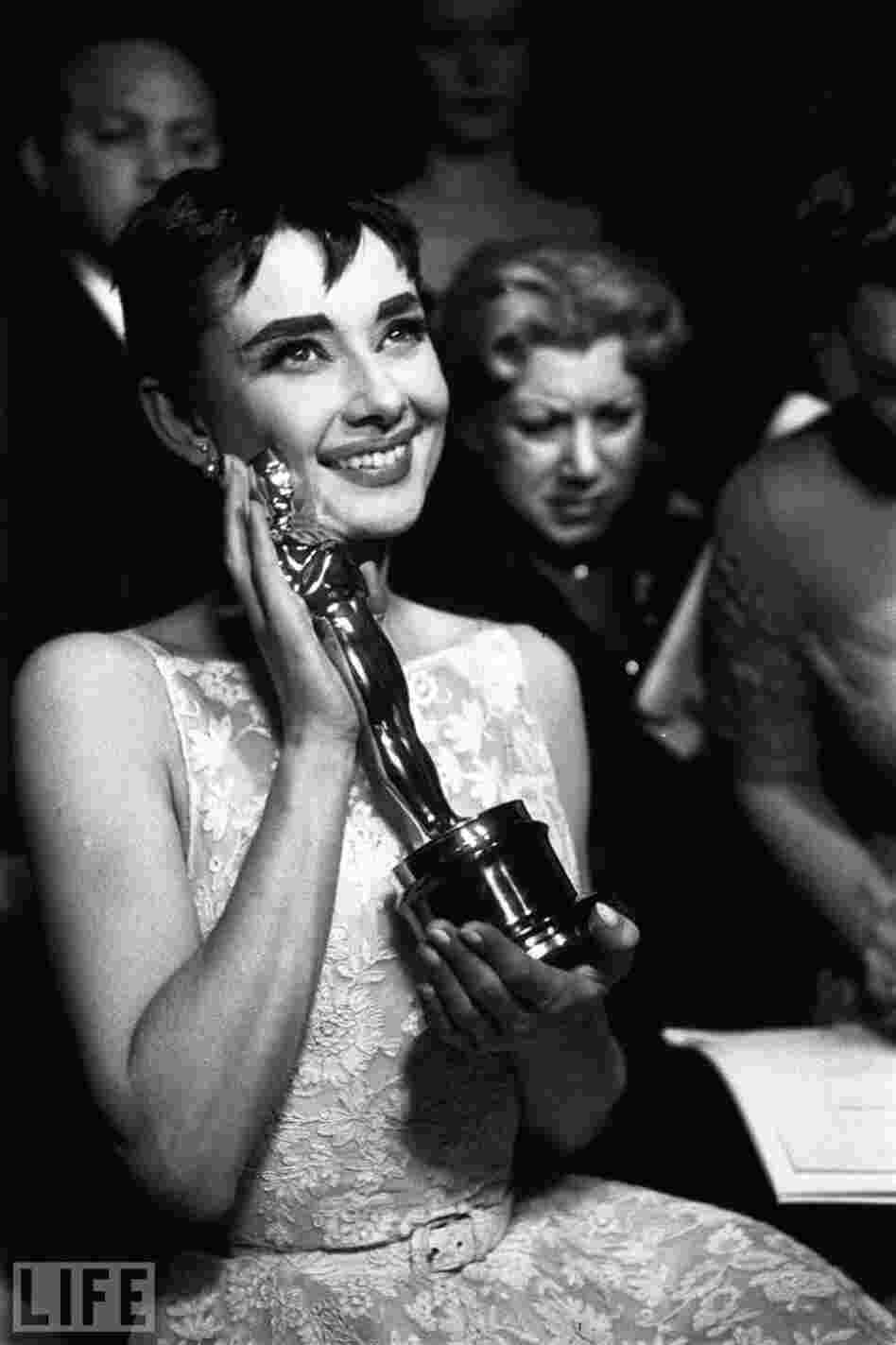 At the 1954 Academy Awards, Audrey Hepburn cradles the Oscar for best actress, awarded for her first lead role and her first Hollywood movie, Roman  Holiday.