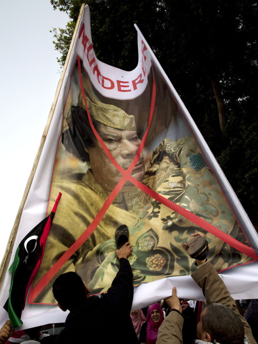 Egyptian protesters beat their shoes against a poster of  Libyan leader Moammar Gadhafi. They gathered Friday in Cairo's Tahrir Square to demand that he step down.