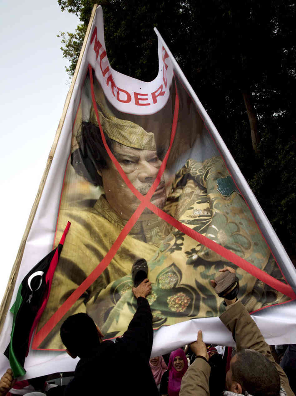 Egyptian protesters beat their shoes against a poster of  Libyan leader Moammar Gadhafi. They gathered Friday in Cairo's Tahrir Square to demand that he step down.