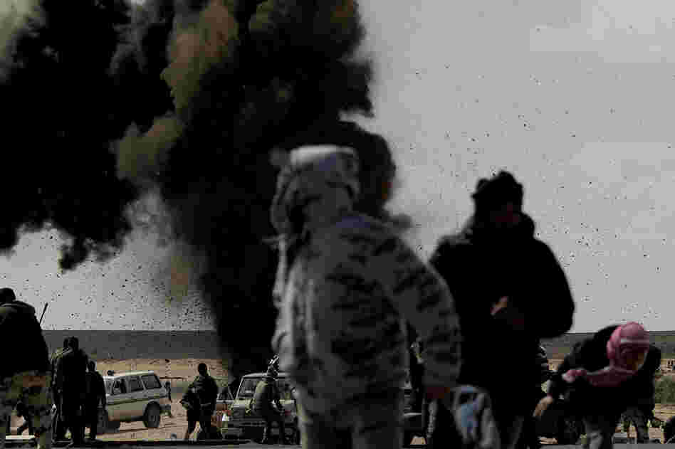 Rebel fighters run for cover as an air force jet drops a bomb on the outskirts of the oil-rich town of Ras Lanuf on Tuesday. 