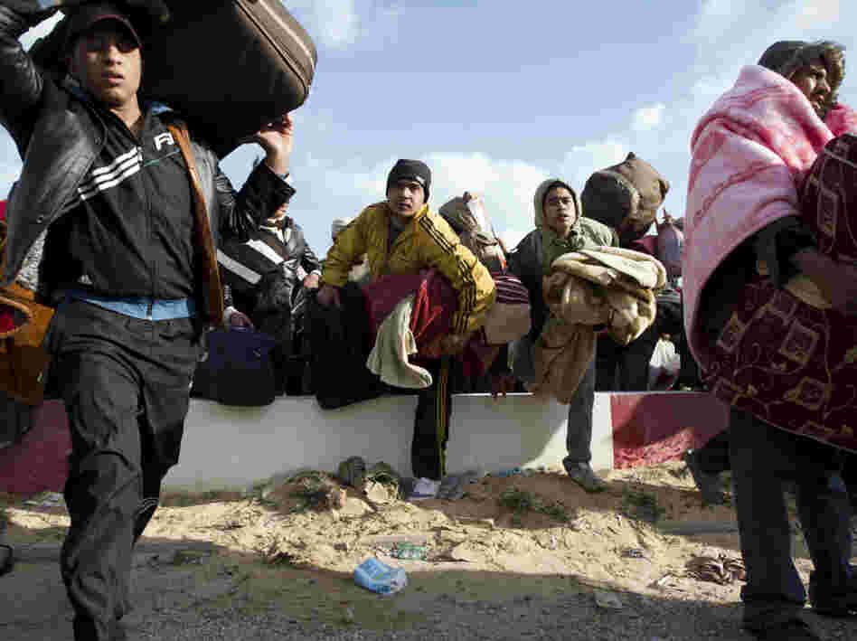 Egyptian people fleeing Libya race to get on buses at the Ras Jedir border post, near the Tunisian city of Ben Guerdane, on Sunday.
