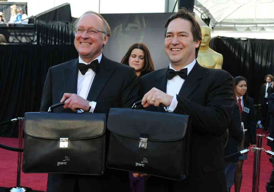 Rick Ross (L) and Brad Oltmann of Price Waterhouse Cooper arrive with briefcases containing the winners' envelopes.