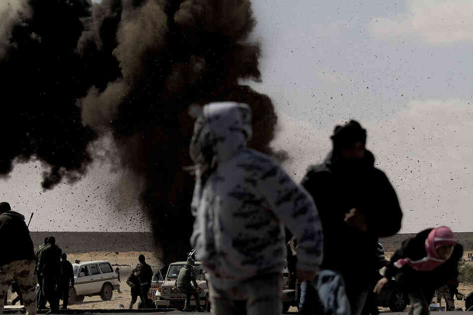 Rebel fighters run for cover as an air force jet drops a bomb on the outskirts of the oil-rich town of Ras Lanuf on Tuesday. 