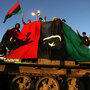 Anti-Gadhafi protesters wave their old national flag as they stand atop an abandoned army tank in the eastern Libyan city of Benghazi on Monday.
