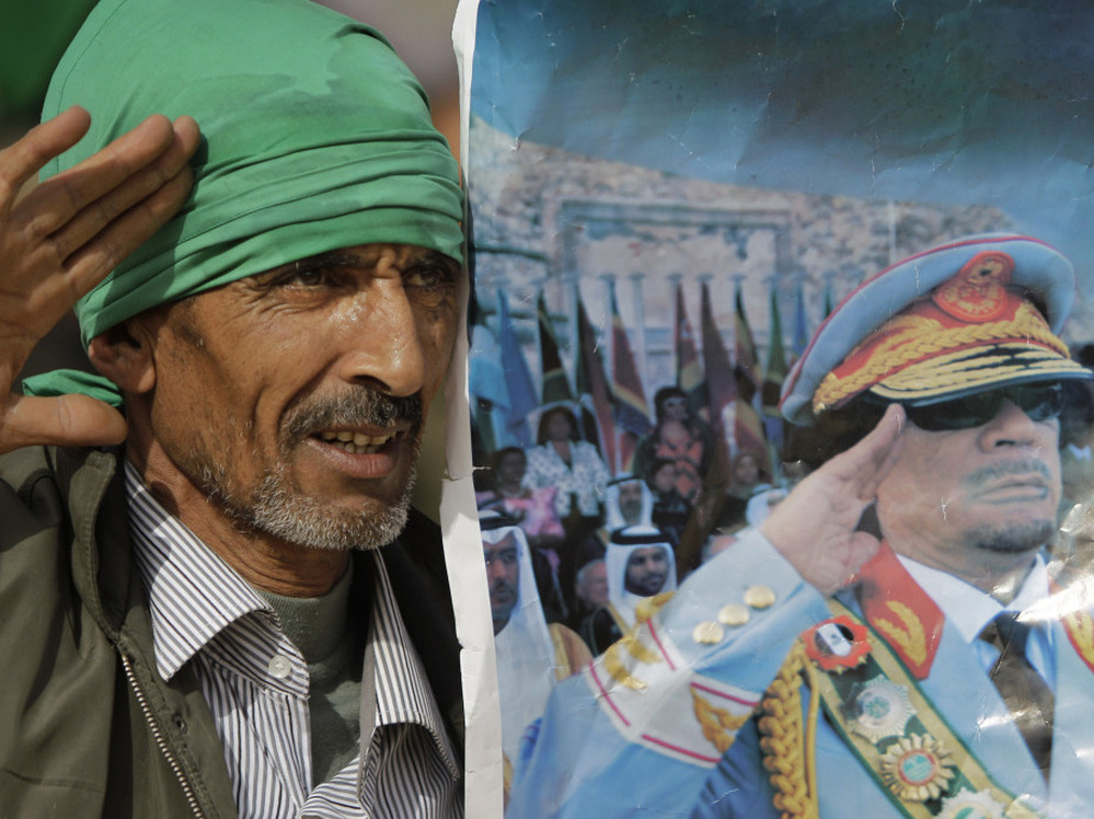 A Gadhafi supporter simulates the salute portrayed in a photograph of Libyan Leader Moammar Gadhafi, as he and others stage a small rally on the stage of the Roman amphitheatre at the Sabratha archaeological site.
