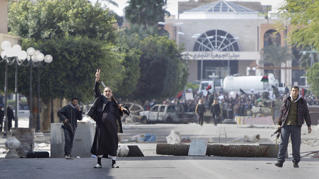 A gunman beckons foreign journalists inside barricades so they can see the main square of Zawiya, west of Tripoli. Reporters have had difficulty both entering Libya and traveling freely once in the country.