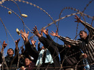 Men reach for food being thrown to them while they wait to enter Tunisia from Libya in the border town of Ra's Ajdir, March 1. U.N. officials say Tunisia cannot cope with the thousands of refugees entering the fragile nation. Men reach for food being thrown to them while they wait to enter Tunisia from Libya in the border town of Ra's Ajdir, March 1. U.N. officials say Tunisia cannot cope with the thousands of refugees entering the fragile nation.