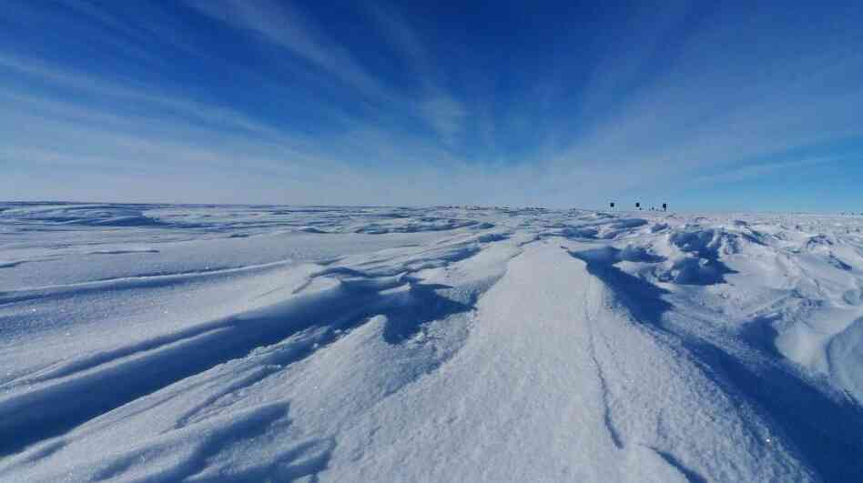The ice surface of Antarctica, looking toward the Gamburtsev Mountains and Dome A. Deep below the surface here, new ice is forming around the mountains and pushing upward. The black flags in the distance mark the edge of the runway for research aircraft studying the area. The ice surface of Antarctica, looking toward the Gamburtsev Mountains and Dome A. Deep below the surface here, new ice is forming around the mountains and pushing upward. The black flags in the distance mark the edge of the runway for research aircraft studying the area.